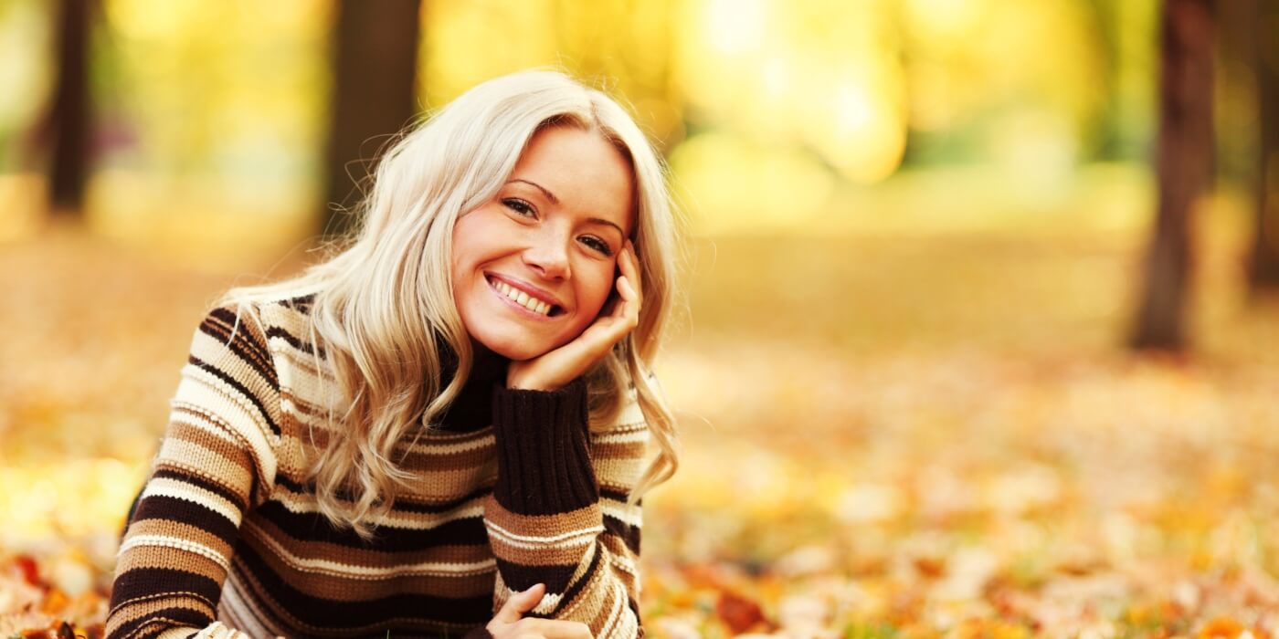 woman wearing striped brown sweater in leaves outside during autumn