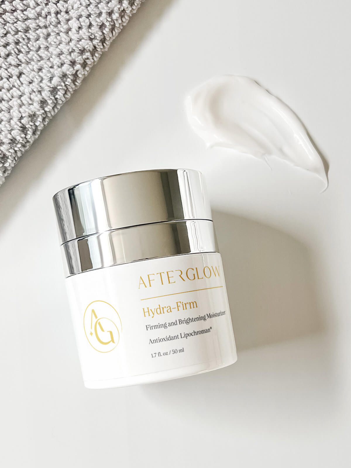 A small canister of a product called 'Afterglow' Hydra Firm firming and brightening moisturizer.