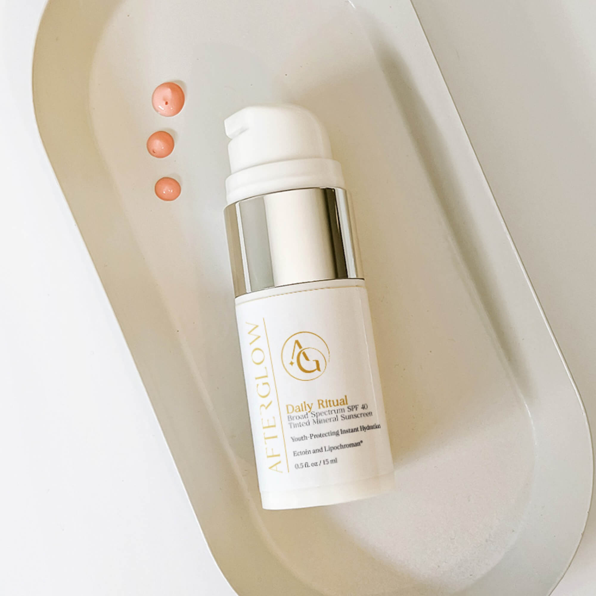 Afterglow Skin Co. Daily Ritual bottle with drops of the product on a neutral background