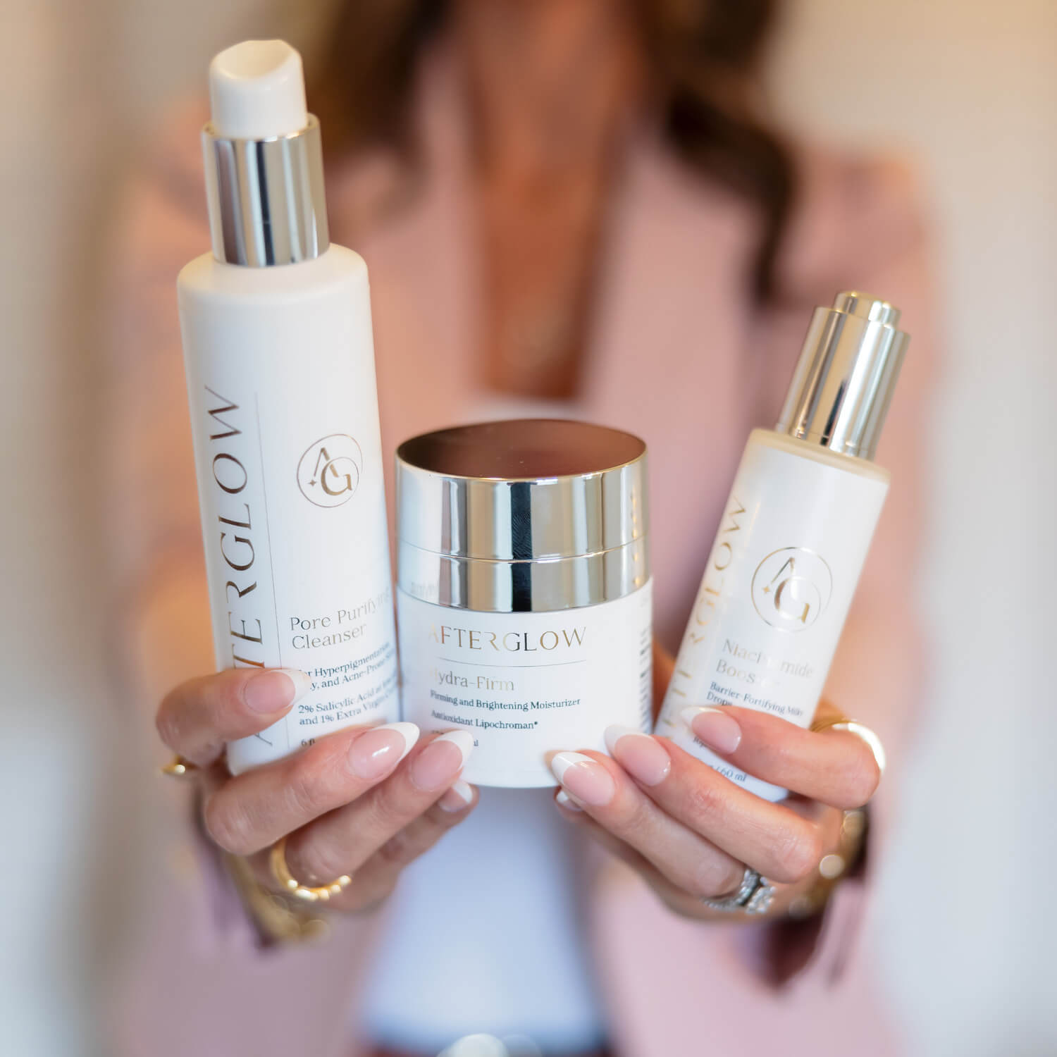 A woman holding up 3 products into focus with her body in the background out of focus.