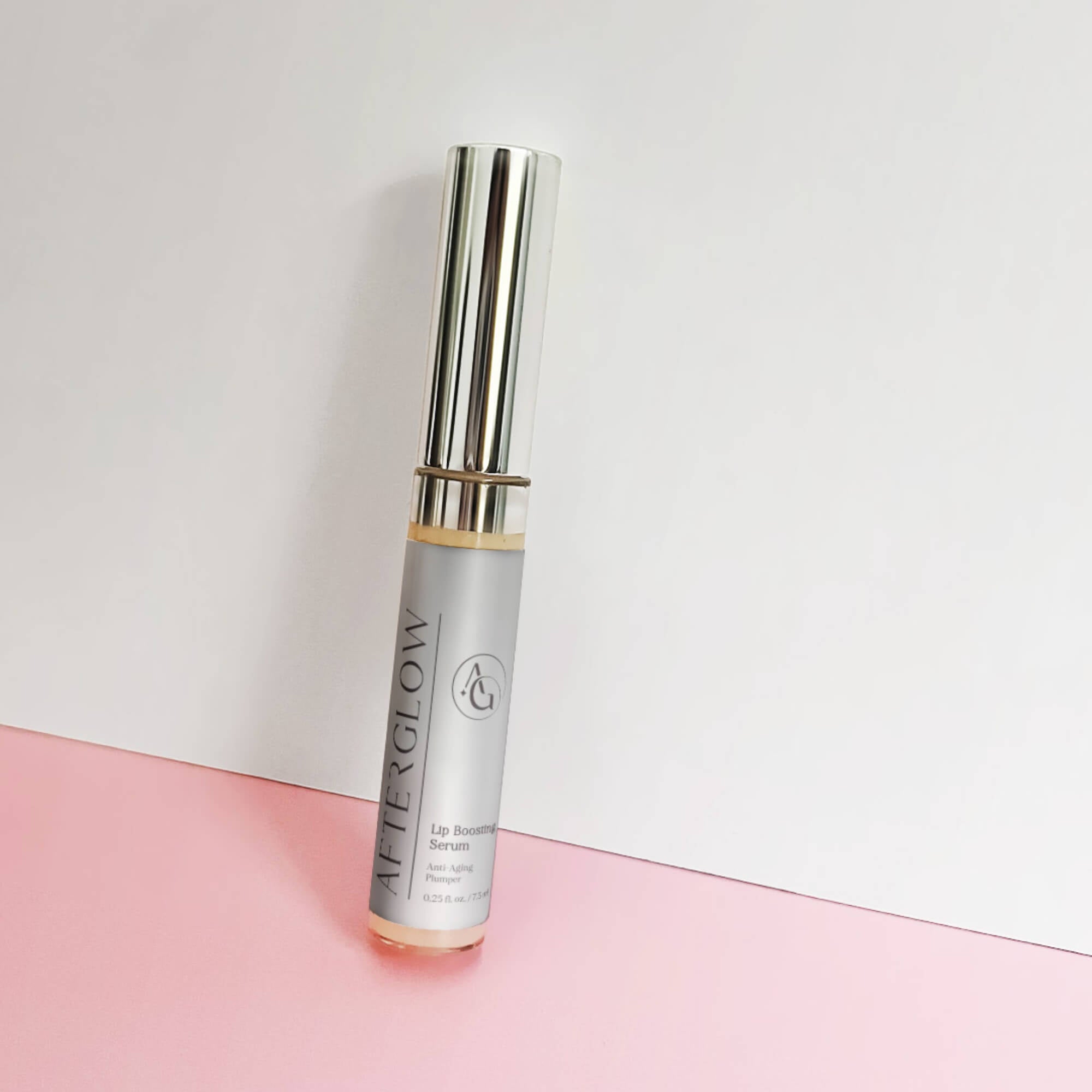 Afterglow Skin Co Lip Boosting Serum with silver packaging on a pink and white background