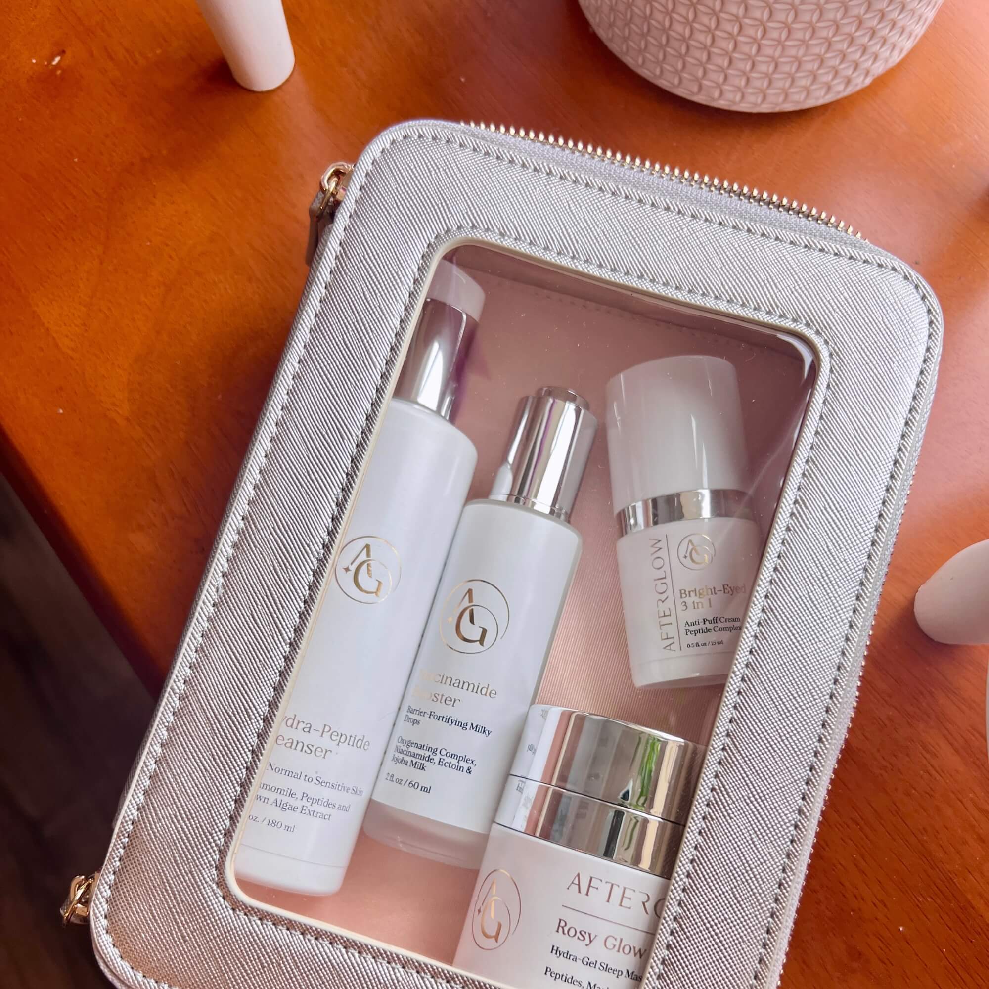 Set of skincare products in a light pink case on a wooden surface
