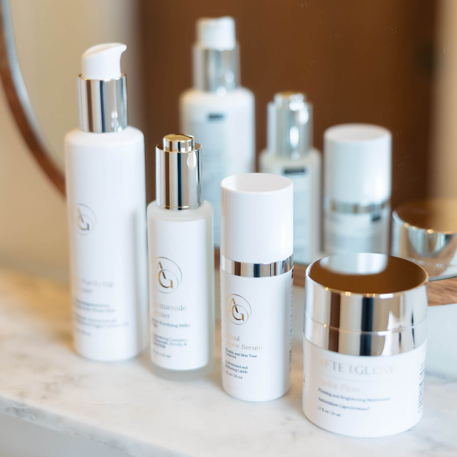 4 bottles of skincare products on a ledge in front of a mirror in a bathroom.