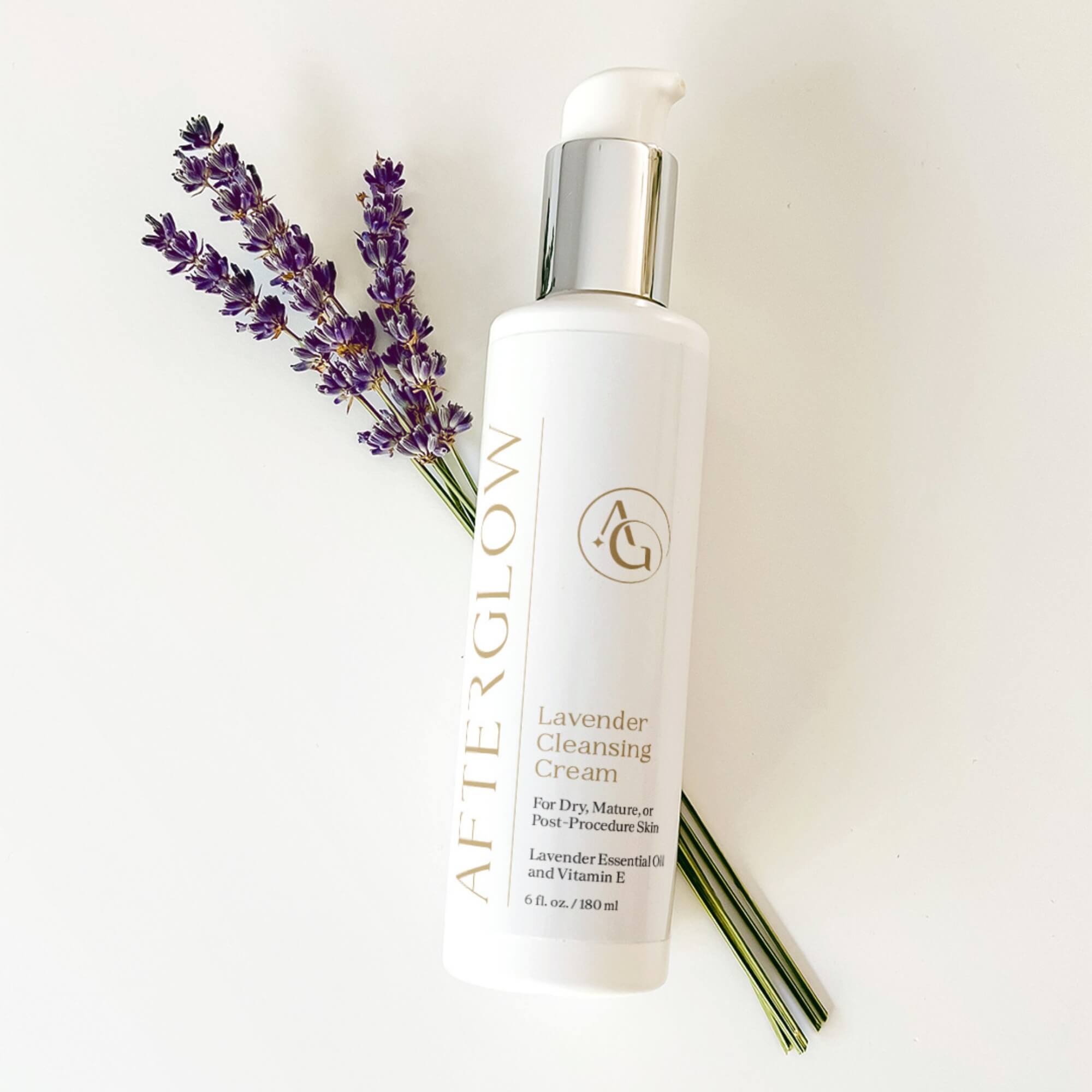 Bottle of 'Afterglow' lavender cleansing cream with lavender flowers on a white background
