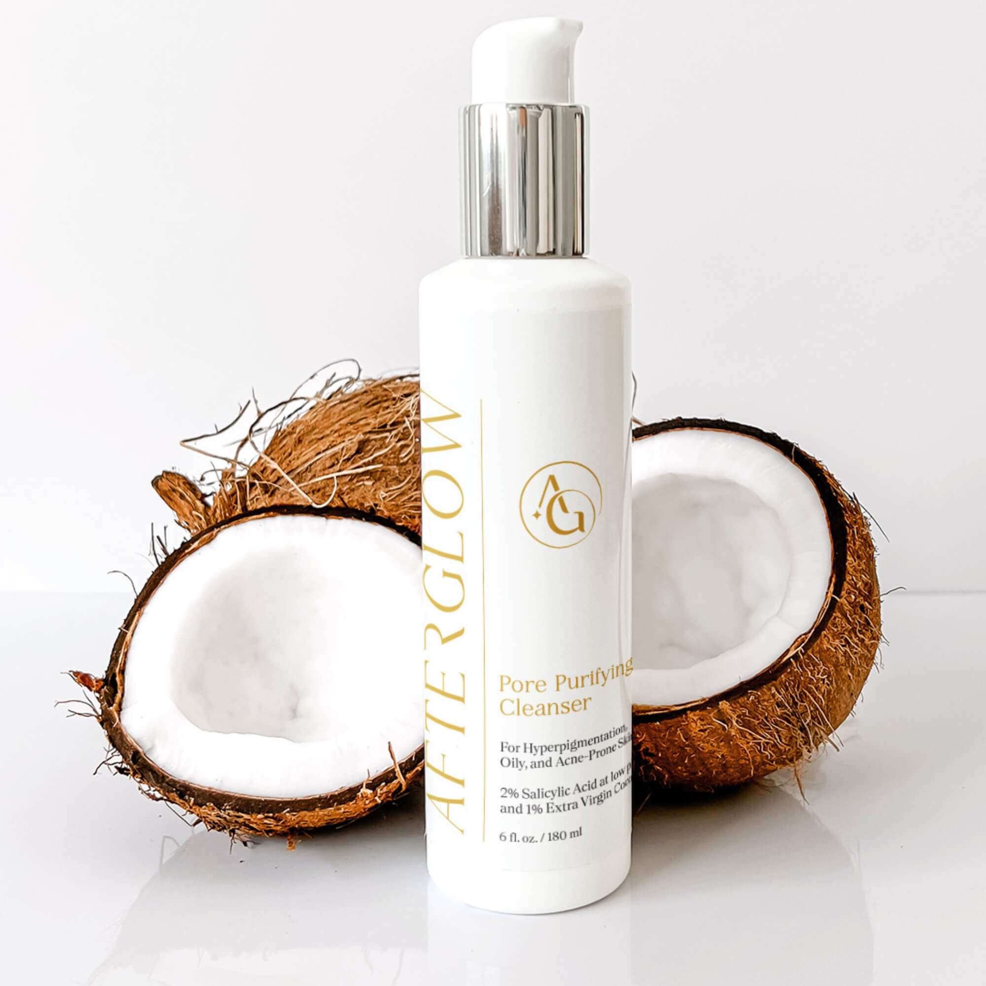 White bottle of Afterglow Skin Co. Pore Purifying Cleanser with a split coconut on a white background