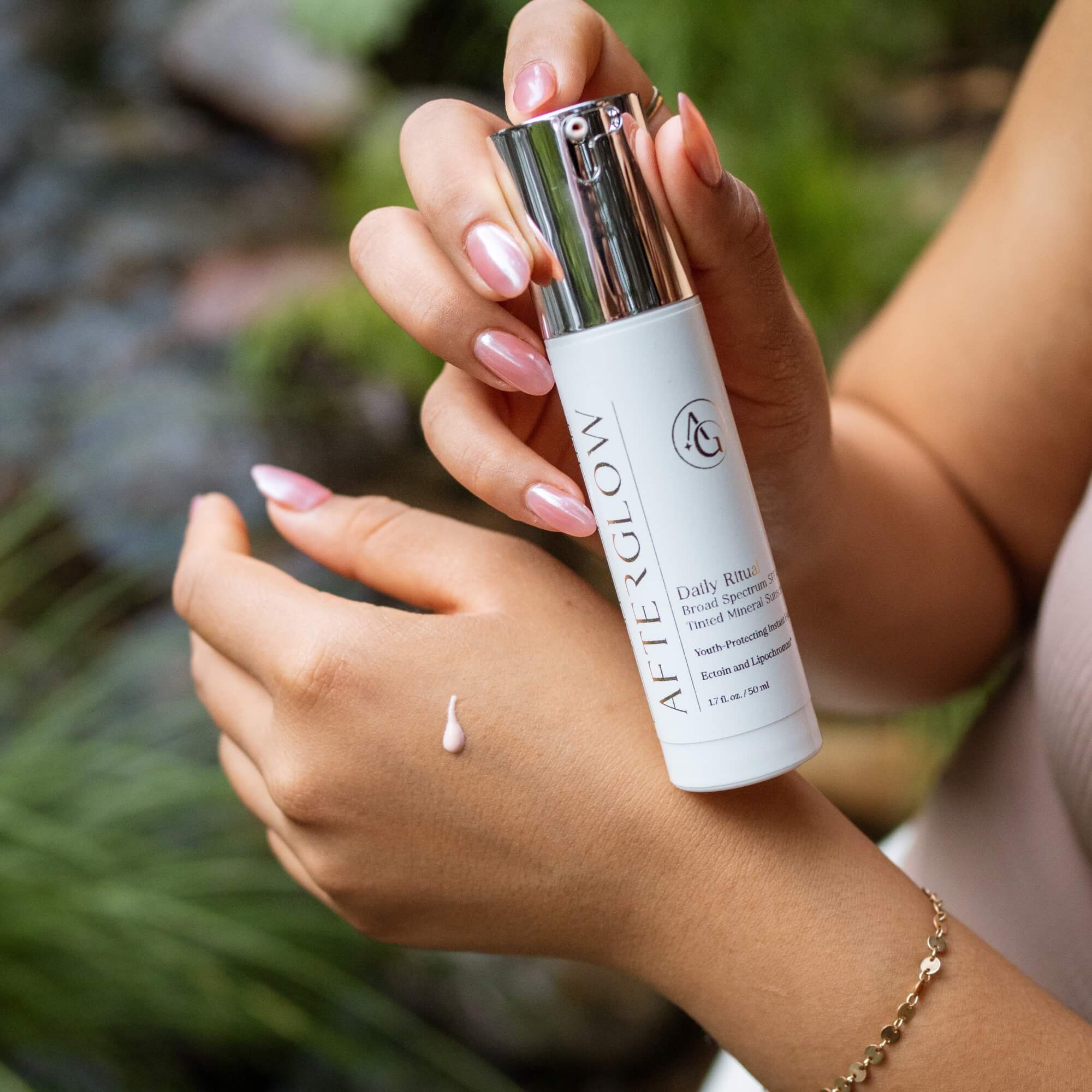 Person applying Afterglow Skin Co. Daily Ritual SPF 40 on their wrist with a blurred natural background