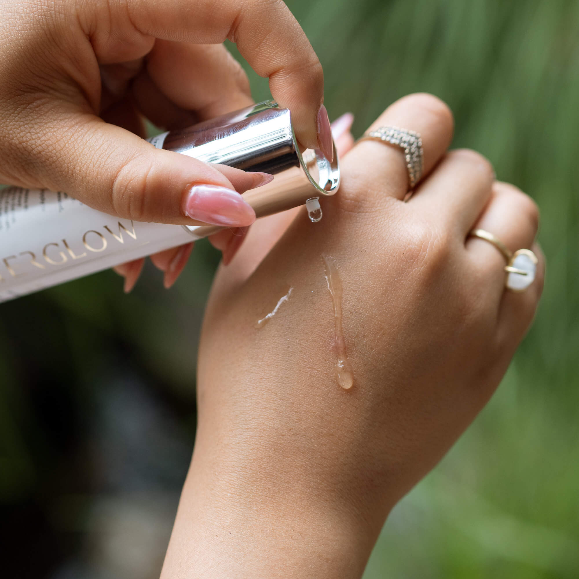Woman applying Afterglow Skin Co. Skin Perfecting Gel to their hand with a blurred natural background